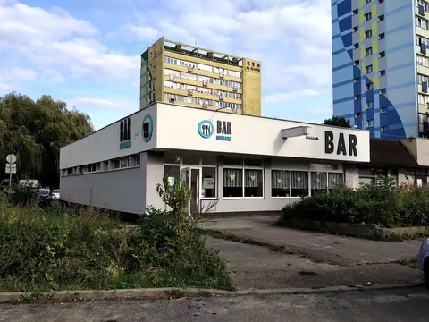 Biały parterowy pawilon z napisem BAR między blokami